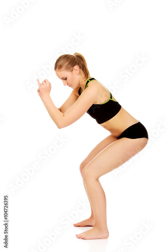 Young athletic woman performs squats