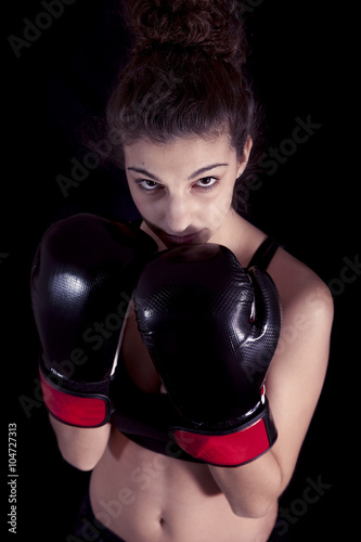  young attractive girl with boxing gloves on black background