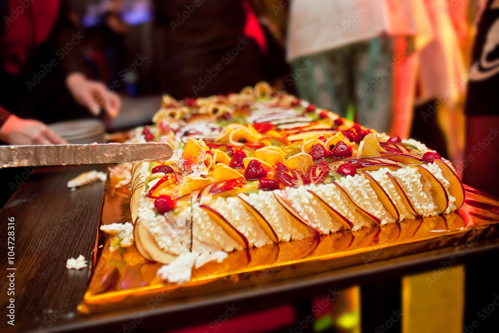 Cutting large cake with berries and fruits Cutting large cake with berries and fruits