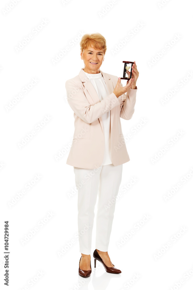 Smile elderly business woman holding sandglass Smile elderly business woman holding sandglass