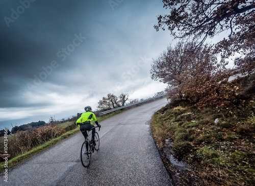 Foto Ciclista percorre una strada in salita sotto la pioggia