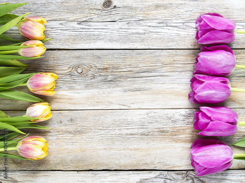 Row of tulips on wooden background with space for message.