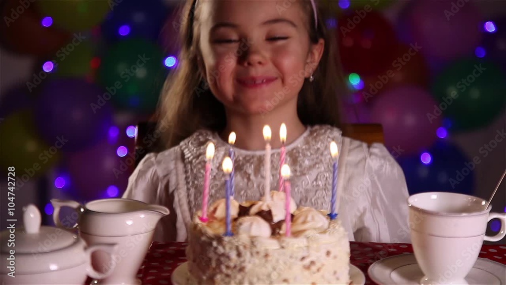 Little girl blowing out the candles of Happy Birthday cake
