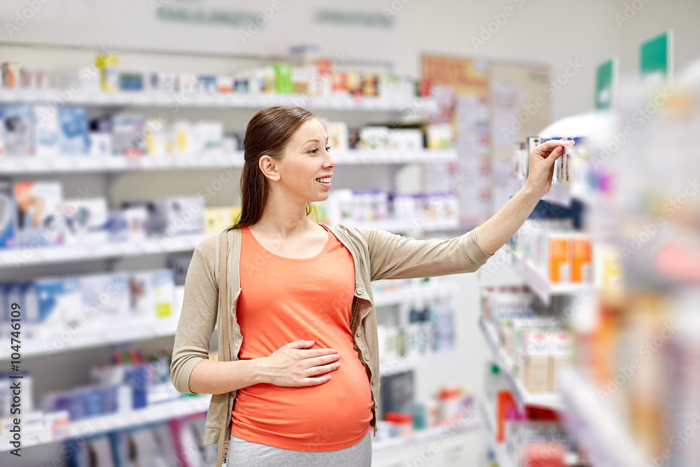 happy pregnant woman choosing medicine at pharmacy