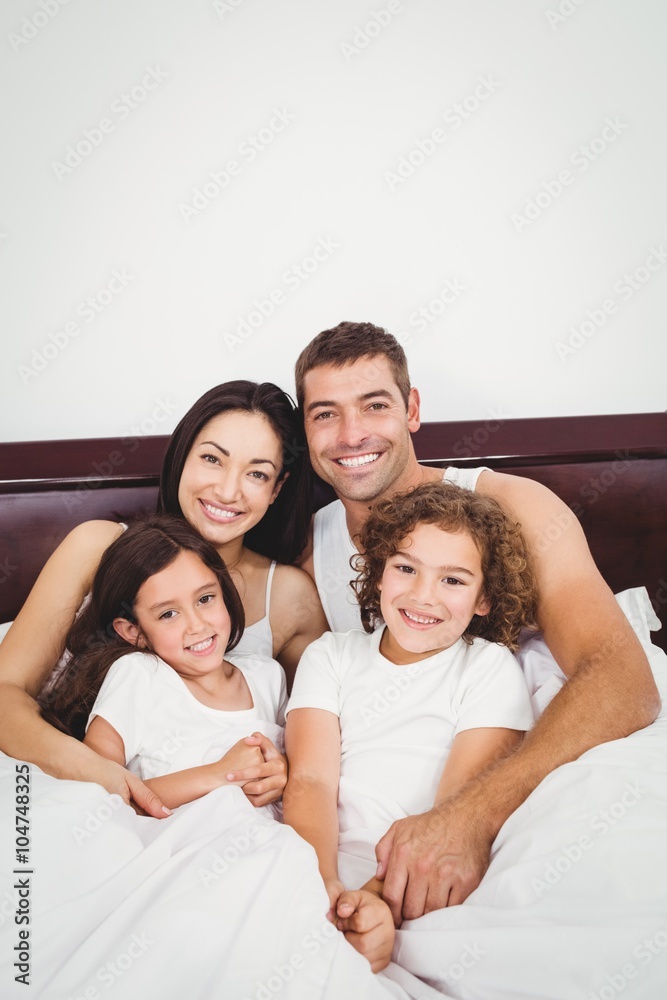 Happy family lying on bed against wall at home