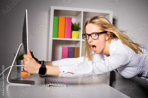 Woman in office holding on to computer photo