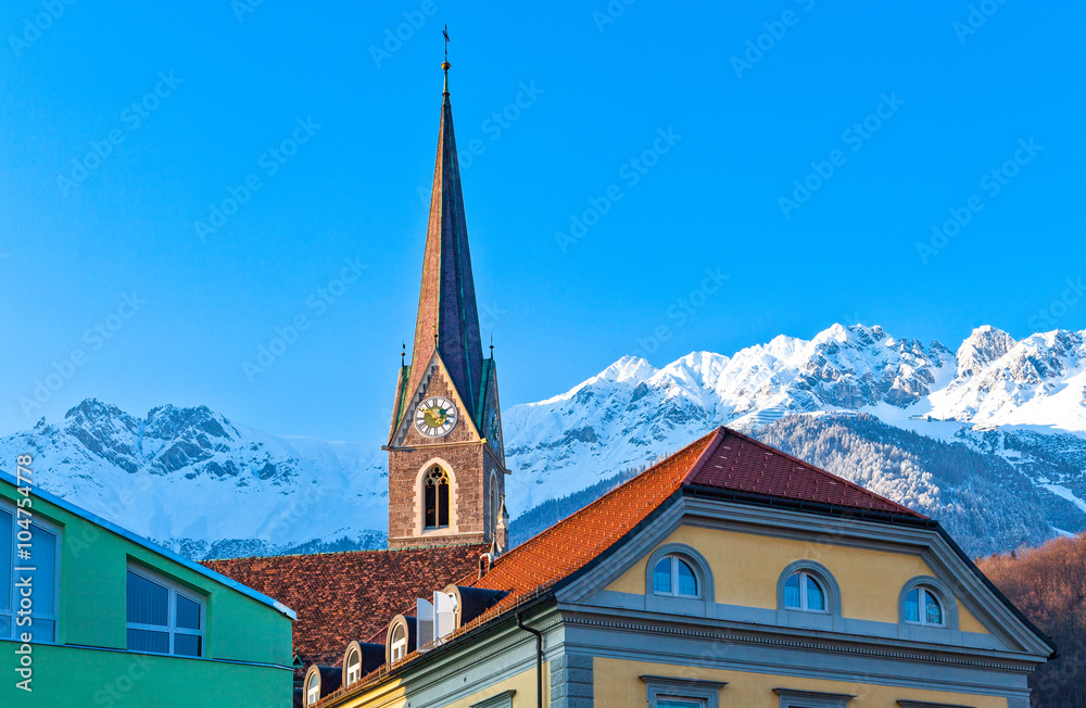 Austria, Innsbruck, view of  the snowy mountains fom the Inn river bank with old houses and bell tower in the foreground