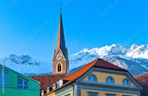 Austria, Innsbruck, view of the snowy mountains fom the Inn river bank with old houses and bell tower in the foreground