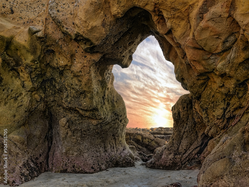 Ghost - The sea sculpted a natural arch in the shape of a ghost. The sunset spills through the archway off the Pacific Ocean coastline in Laguna Beach, California.