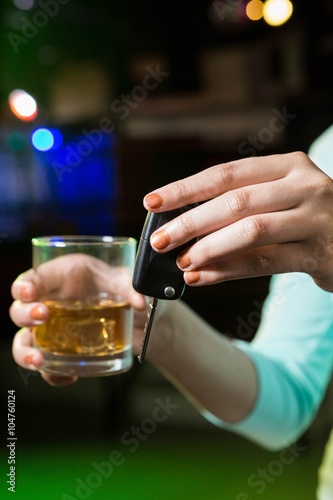 Woman holding a glass of whiskey and car keys