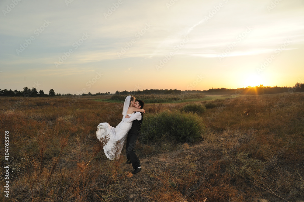 Obraz premium Bride and Groom in the Field at Sunset