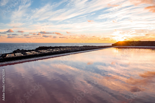 Volcanic pool on the salt manufaturing with pink salt water and sky reflection on the sunset on La Palma island