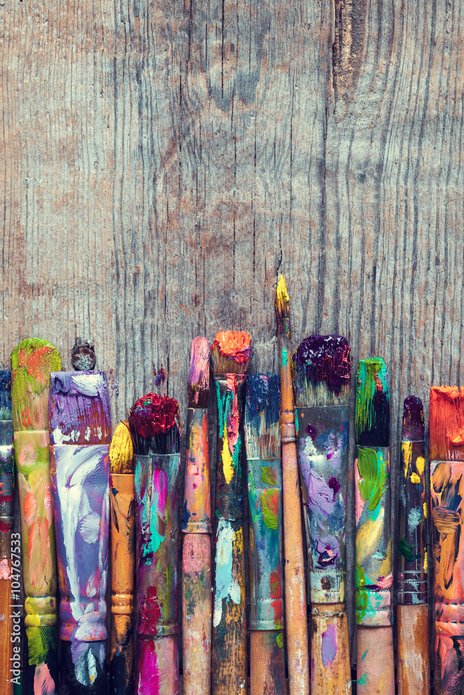 Obraz premium Row of artist paint brushes closeup on old rustic wooden backgro