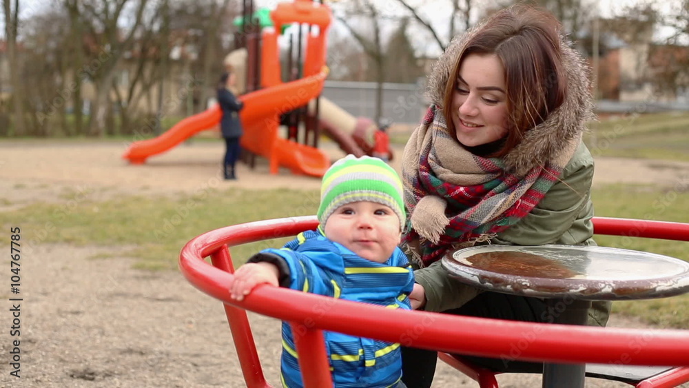 Mother with kid sitting on the carousel on the playground
Mother with kid sitting on the carousel on the playground