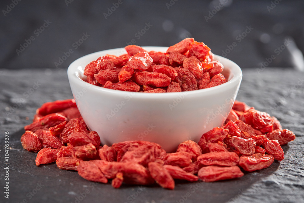 Red goji berries in bowl on stone plate Red goji berries in bowl on stone plate