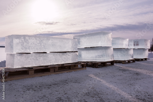 Row of large ice cubes piled on wooden pallets photo