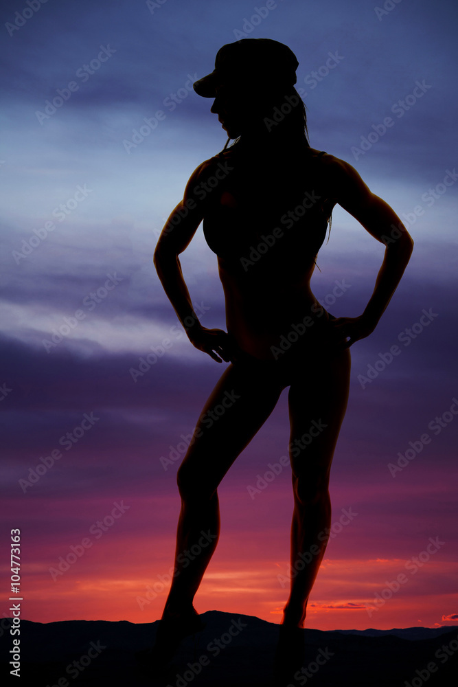 silhouette of a woman in bikini and hat hands on hips