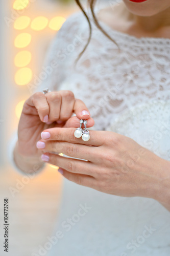 pearl earrings in the hands of the bride