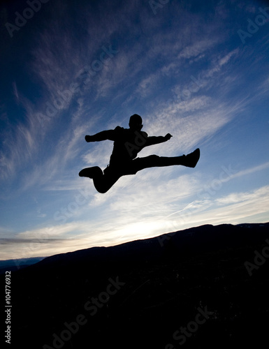 silhouette of a person jumping against the sunset sky