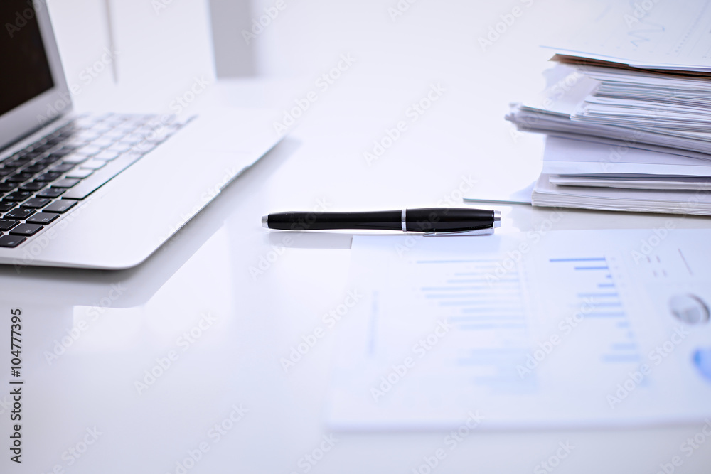 .Office workplace with a laptop and financial documents on the light reflecting table .Office workplace with a laptop and financial documents on the light reflecting table