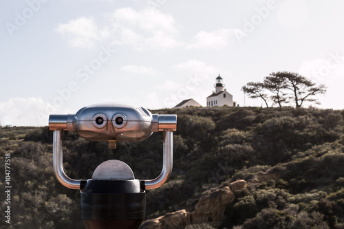 Sightseeing binoculars with Old Point Loma lighthouse in the distance in San Diego, California.