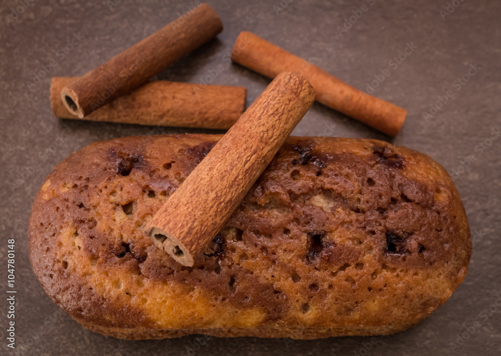 Cinnamon sticks and cake with jam on light brown background Cinnamon sticks and cake with jam on light brown background