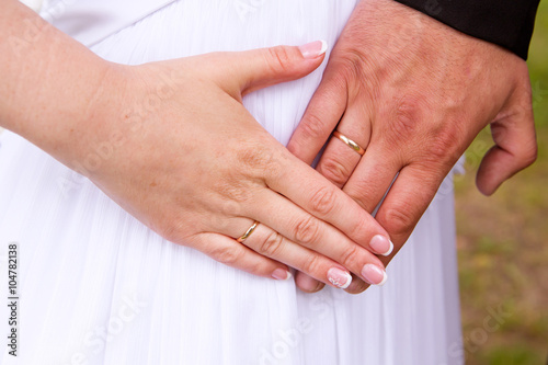 Wedding couple hands with wedding rings on woman's belly