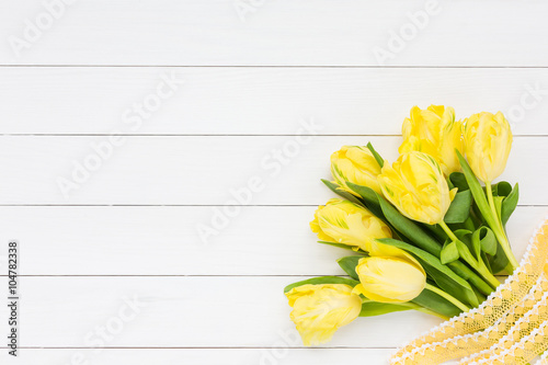 Bouquet of yellow tulips with ribbon  on white wooden background. Top view, copy space
