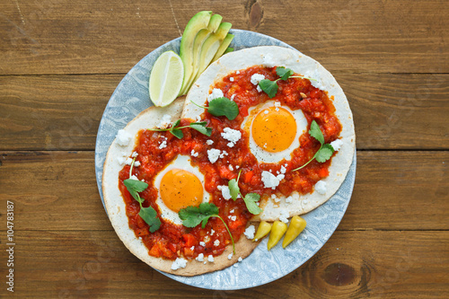 Mexican breakfast huevos rancheros: fried egg with salsa closeup in the pan photo