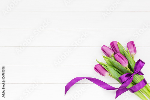 Fototapeta Naklejka Na Ścianę i Meble -  Bouquet of five tulips with ribbon bow on white wooden background. Top view, copy space