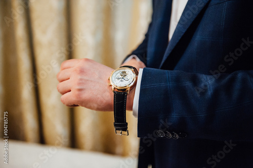 groom clasping stylish watch band on his wrist