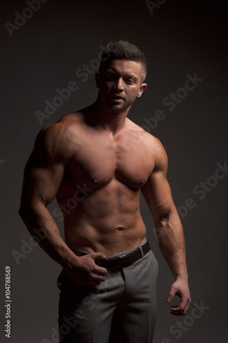 shirtless muscular man in pants posing in studio