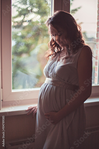Pregnant woman looking thoughtfully at belly