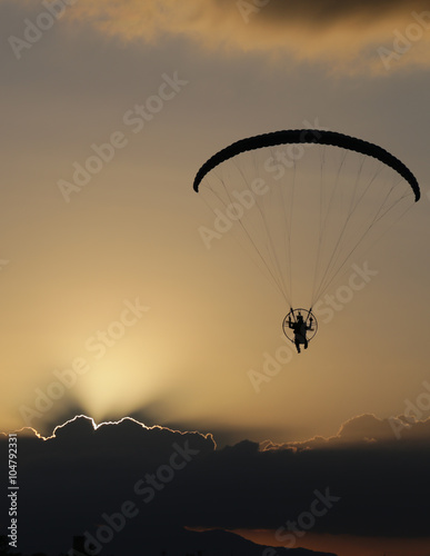 Silhouette paramotor / paraglider flying on sky.