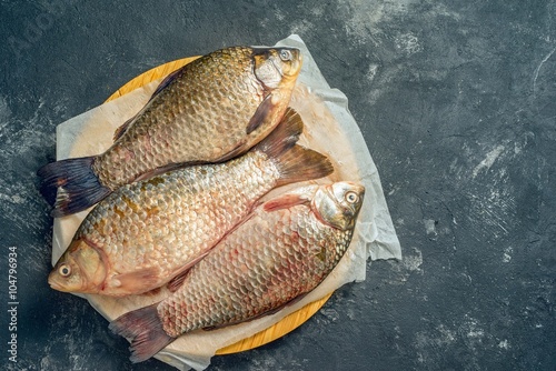 Three fresh carp on wooden board, top view, with copy space photo