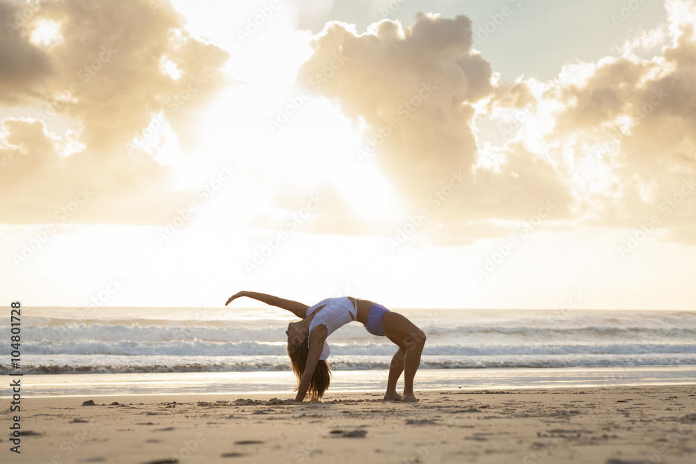 Fit woman stretching on beach at sunrise