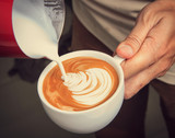 Latte art, barista pouring milk to make coffee latte art in vint