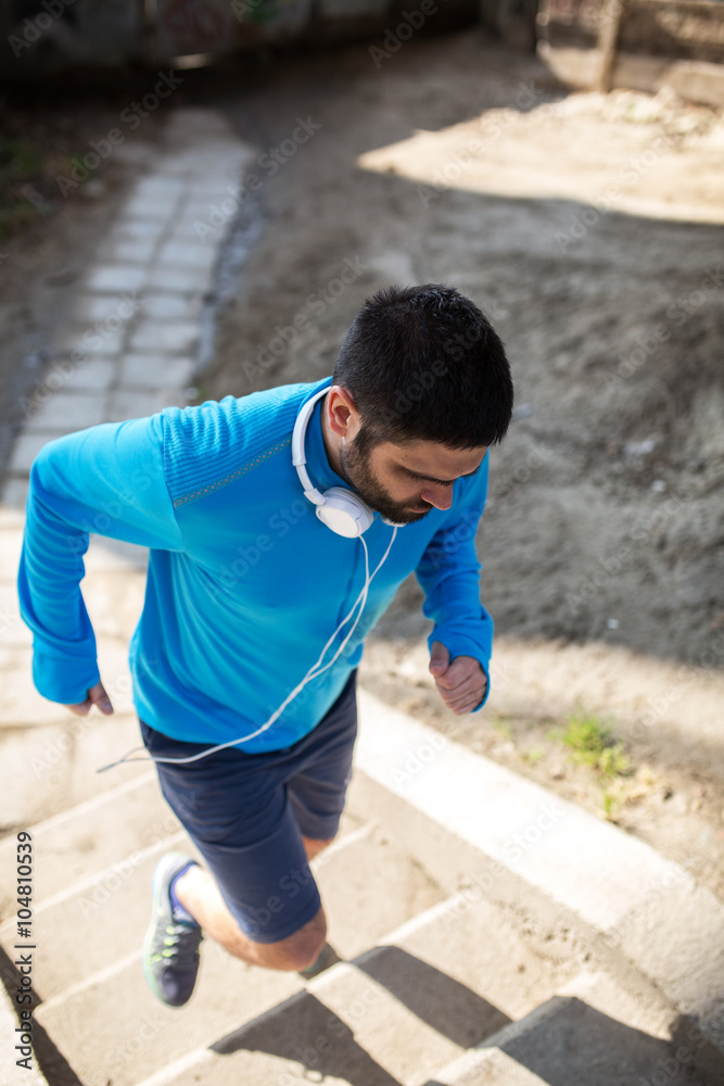 Man in blue shirt running up the stairs. Cross fit training.City environment.