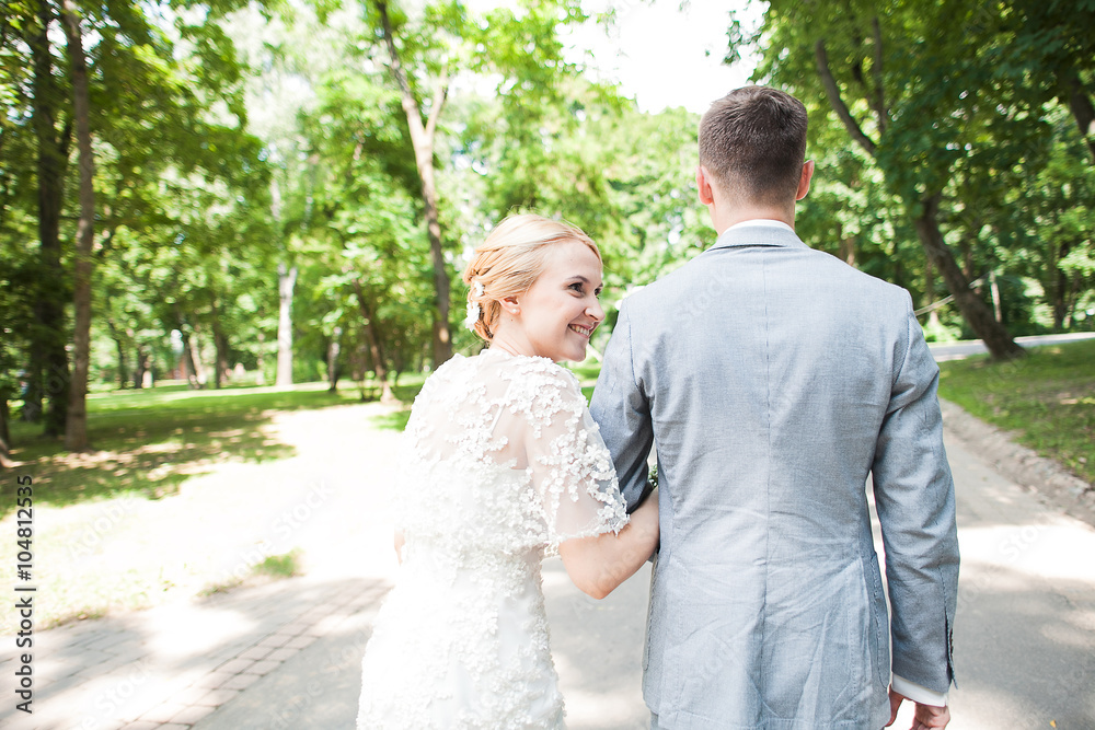 Bride and groom walking away in summer park outdoors Bride and groom walking away in summer park outdoors