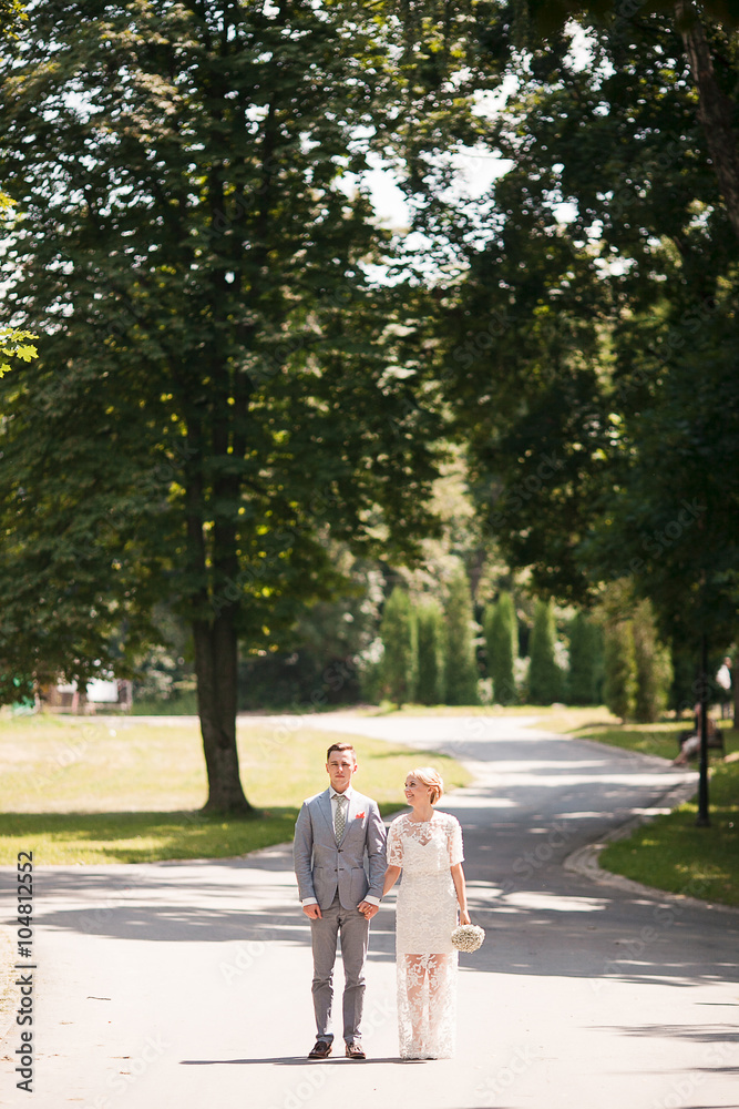 Bride and groom walking away in summer park outdoors Bride and groom walking away in summer park outdoors