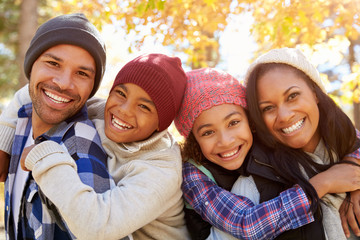 Parents Giving Children Piggyback Ride On Walk In Woods