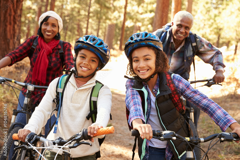 Obraz premium Grandparents With Children Cycling Through Fall Woodland