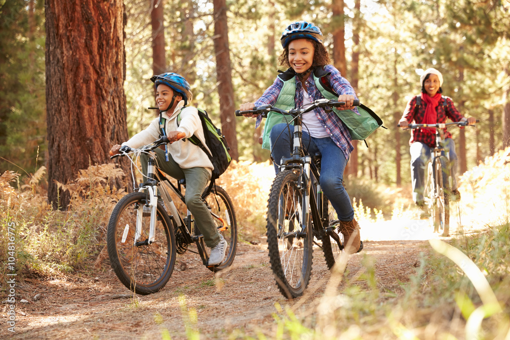 Fototapeta premium Grandparents With Children Cycling Through Fall Woodland