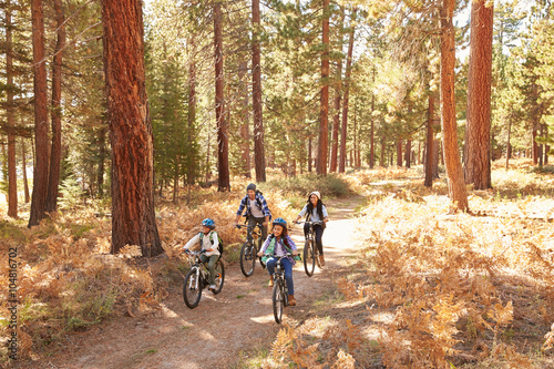 African American Family Cycling Through Fall Woodland