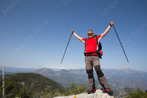 Hiker standing on top of the mountain with valley on the background.