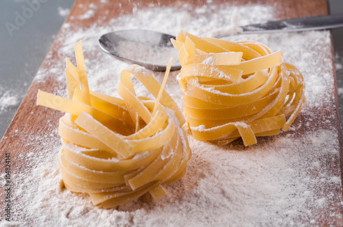 raw tagliatelle with flour on brown wooden table
