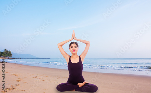 young woman practicing yoga on the beach