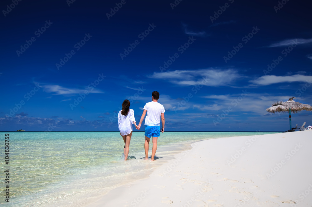 Back view of young couple on white beach. Vacation concept