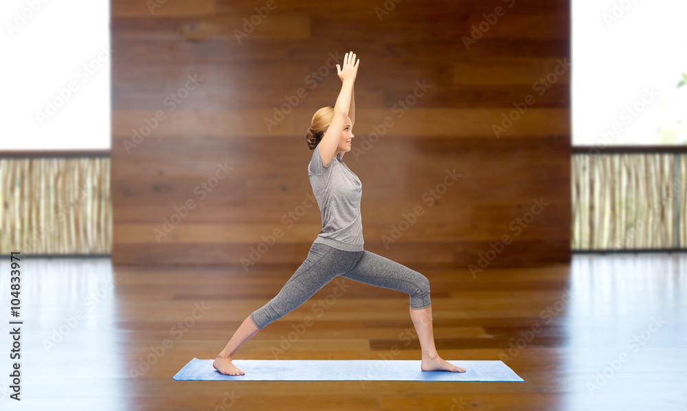Fototapeta premium woman making yoga warrior pose on mat