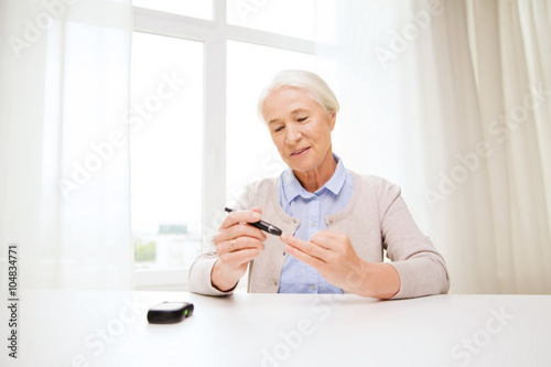 senior woman with glucometer checking blood sugar © Syda Productions